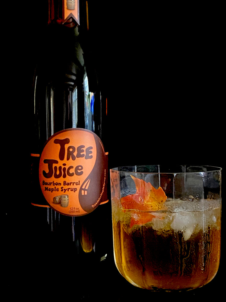 12oz bottle of Tree Juice Bourbon barrel aged maple syrup with a cocktail
